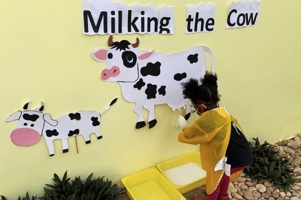 milking the cow game with milk filled glove under a paper cow