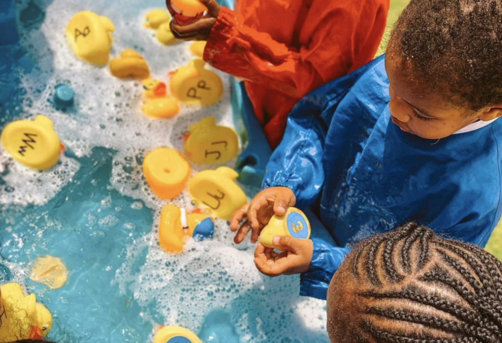 children learning the alphabet using rubber ducks in a pool